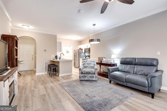 living room featuring ceiling fan, light hardwood / wood-style floors, ornamental molding, and sink