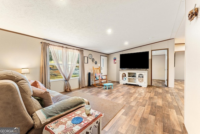 living room with a textured ceiling, ornamental molding, lofted ceiling, and hardwood / wood-style flooring