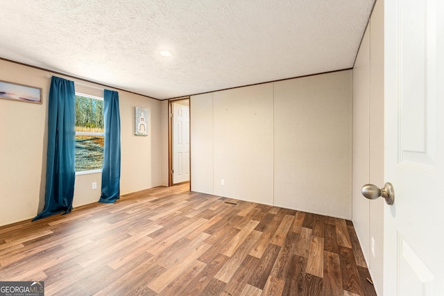 spare room featuring wood-type flooring and a textured ceiling