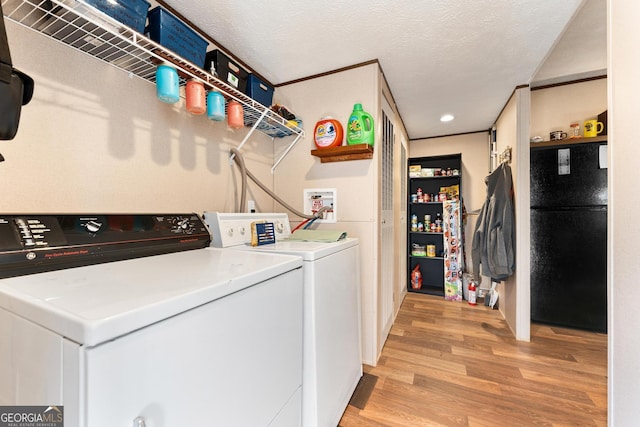 washroom with washer and dryer, a textured ceiling, and light hardwood / wood-style flooring