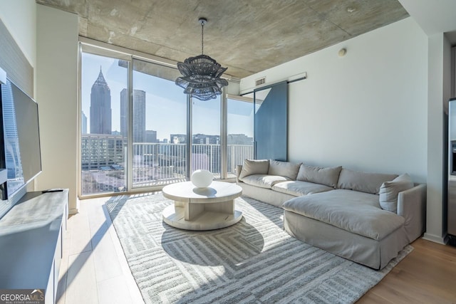 living room featuring expansive windows, light wood-type flooring, and a chandelier