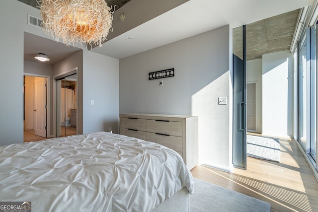 bedroom with light wood-style floors, a chandelier, and visible vents