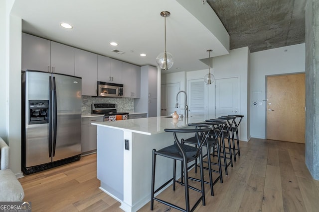 kitchen with stainless steel appliances, tasteful backsplash, sink, hanging light fixtures, and a breakfast bar area