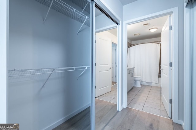 walk in closet with light wood finished floors and visible vents