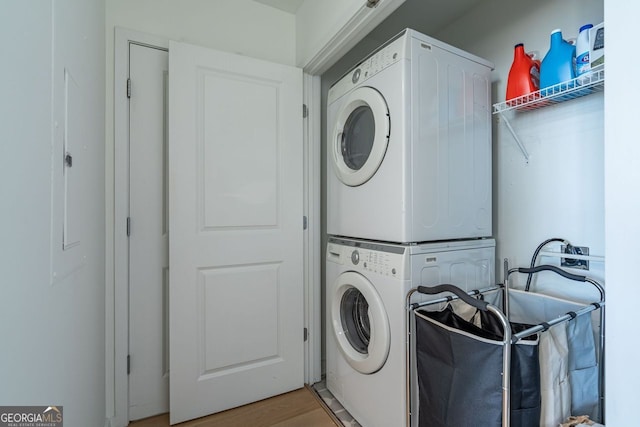 laundry area with laundry area, wood finished floors, and stacked washer and clothes dryer