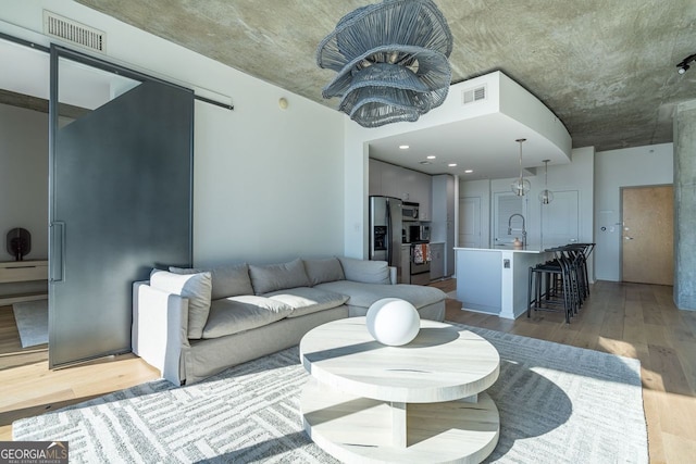 living room with sink, a chandelier, and light hardwood / wood-style floors