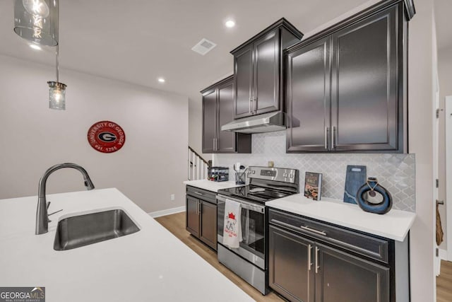 kitchen featuring sink, backsplash, wood-type flooring, decorative light fixtures, and stainless steel range with electric stovetop