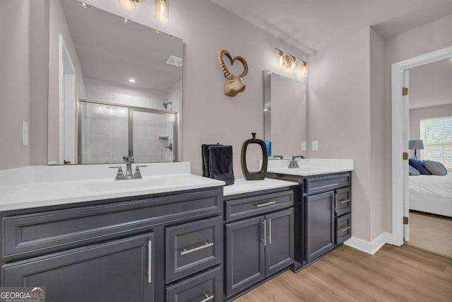 bathroom with wood-type flooring, vanity, and a shower with shower door