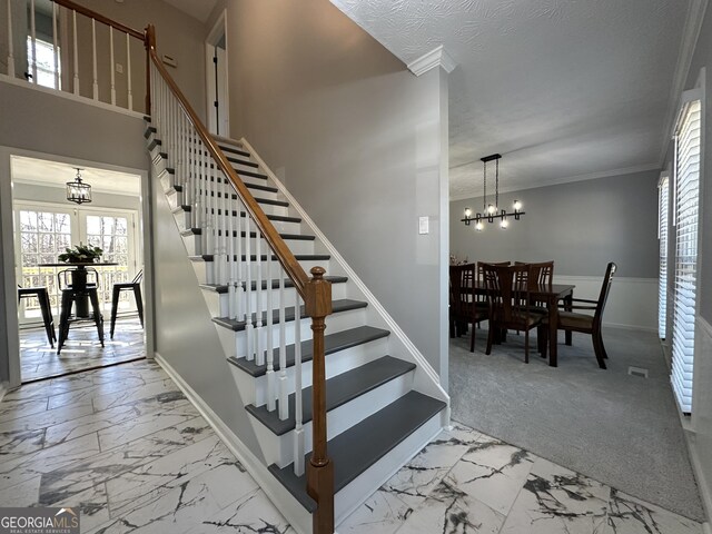 stairway with crown molding and a textured ceiling