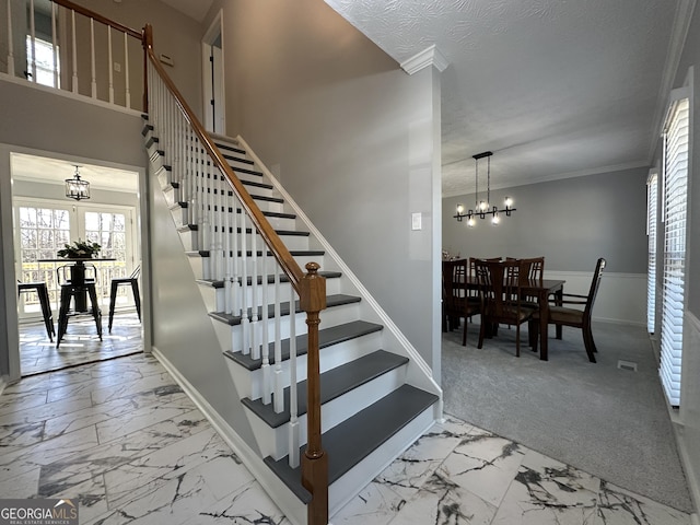 stairs featuring ornamental molding, a chandelier, and carpet