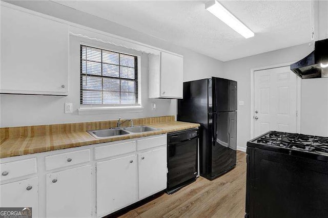 kitchen featuring sink, light hardwood / wood-style floors, a textured ceiling, white cabinets, and black appliances