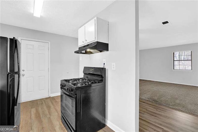 kitchen featuring white cabinets, light hardwood / wood-style floors, and black appliances