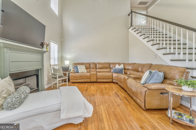 living room featuring light wood-type flooring and a high ceiling