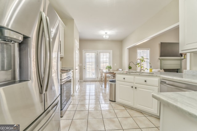 kitchen featuring white cabinetry, sink, light stone counters, light tile patterned floors, and appliances with stainless steel finishes