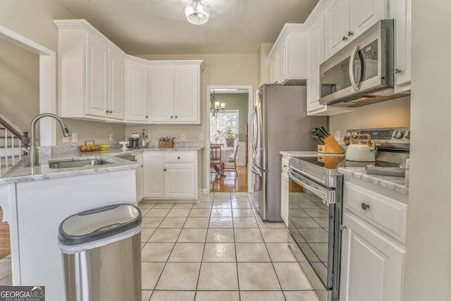 kitchen with light stone counters, white cabinetry, stainless steel appliances, and light tile patterned floors