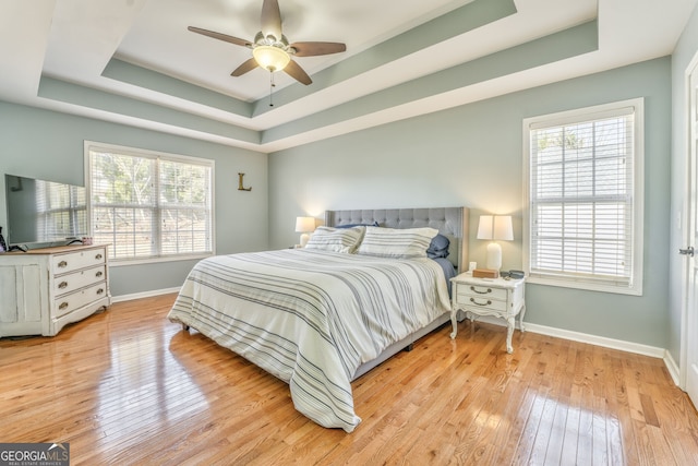 bedroom featuring a tray ceiling, ceiling fan, and light hardwood / wood-style floors