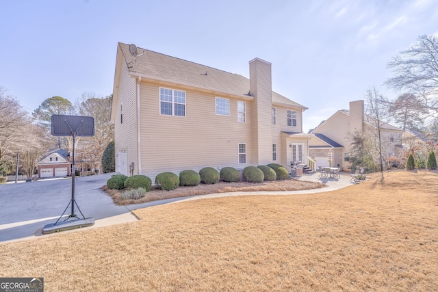 back of house featuring a lawn and a garage