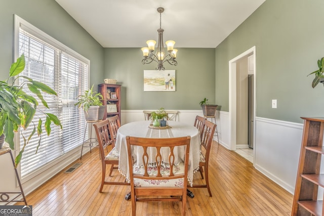 dining space with light hardwood / wood-style floors and an inviting chandelier