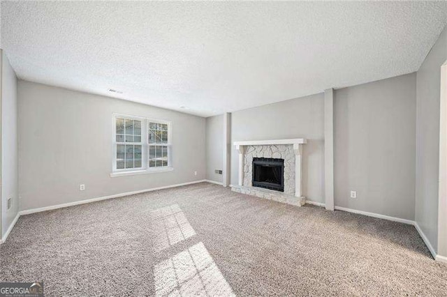 unfurnished living room with a fireplace, carpet floors, and a textured ceiling