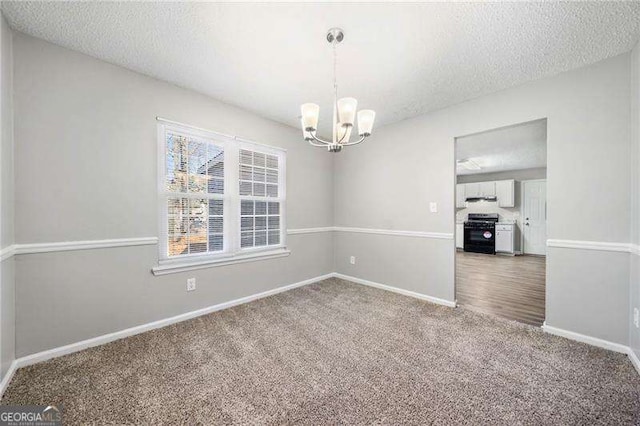 carpeted spare room with a textured ceiling and a chandelier