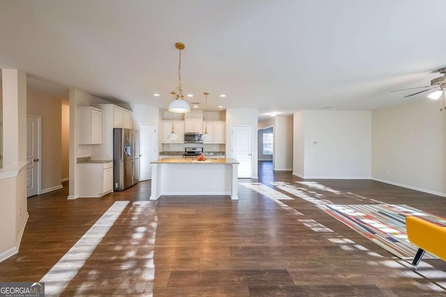 kitchen featuring light stone countertops, an island with sink, decorative light fixtures, white cabinetry, and stainless steel appliances