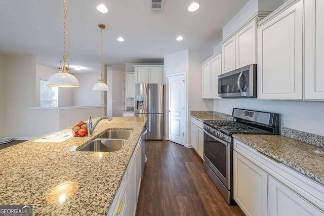 kitchen with light stone countertops, sink, white cabinets, and stainless steel appliances