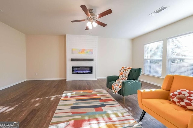 sitting room featuring ceiling fan, a fireplace, and dark hardwood / wood-style floors