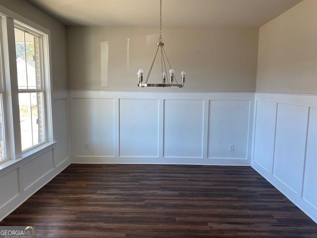 unfurnished dining area featuring dark hardwood / wood-style floors and an inviting chandelier