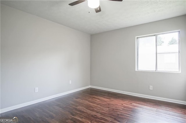 spare room with dark wood-type flooring and ceiling fan