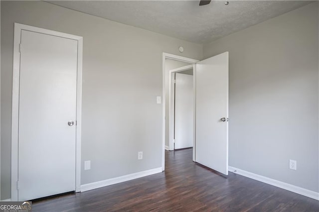 unfurnished bedroom featuring dark wood-type flooring, ceiling fan, and a textured ceiling