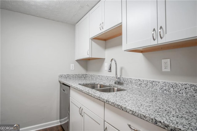 kitchen with sink, light stone counters, a textured ceiling, white cabinets, and stainless steel dishwasher