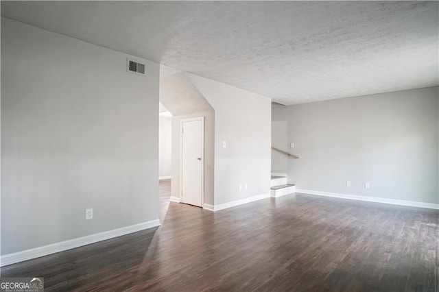 unfurnished living room with dark wood-type flooring and a textured ceiling