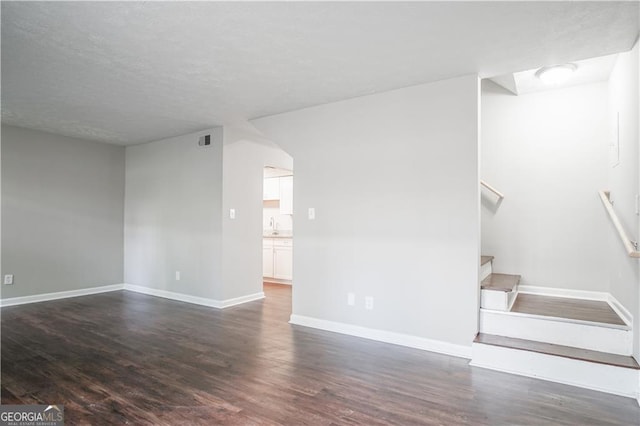 unfurnished living room featuring sink and dark wood-type flooring