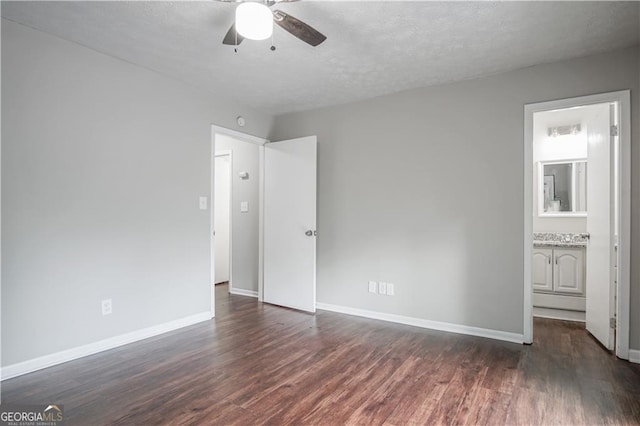 unfurnished bedroom featuring connected bathroom, a textured ceiling, dark wood-type flooring, and ceiling fan