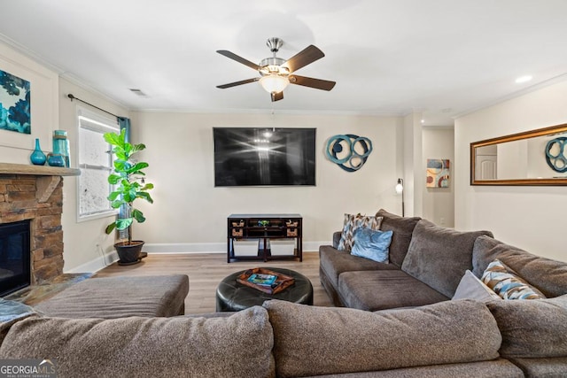 living room with ceiling fan, a fireplace, crown molding, and light wood-type flooring