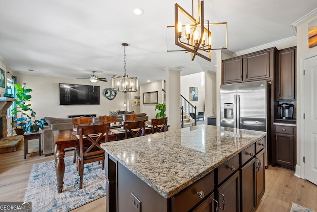 kitchen featuring ceiling fan with notable chandelier, dark brown cabinetry, decorative light fixtures, light hardwood / wood-style flooring, and a kitchen island