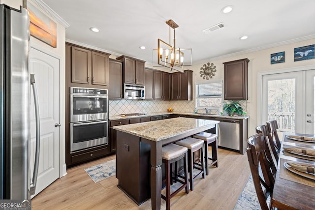 kitchen featuring plenty of natural light, a kitchen island, hanging light fixtures, and appliances with stainless steel finishes