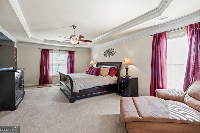 carpeted bedroom with a tray ceiling, ceiling fan, and ornamental molding