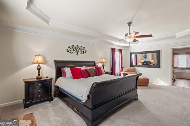 carpeted bedroom featuring ceiling fan, a raised ceiling, ornamental molding, and connected bathroom