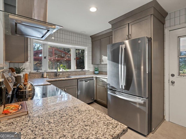 kitchen with decorative backsplash, light stone counters, ventilation hood, stainless steel appliances, and sink