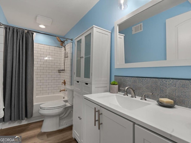 full bathroom featuring tasteful backsplash, vanity, shower / bathtub combination with curtain, hardwood / wood-style floors, and toilet