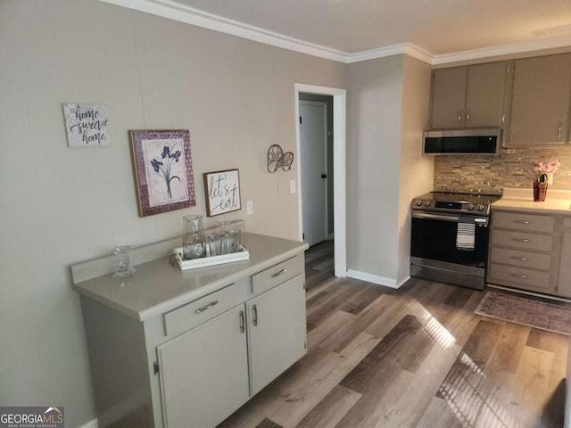 kitchen featuring decorative backsplash, light hardwood / wood-style floors, crown molding, and stainless steel appliances