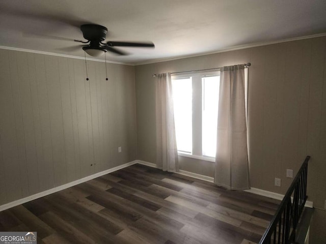 unfurnished room featuring wood walls, dark hardwood / wood-style floors, ceiling fan, and ornamental molding