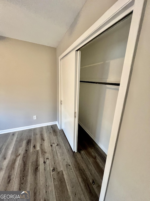 unfurnished bedroom with wood-type flooring, a textured ceiling, and a closet