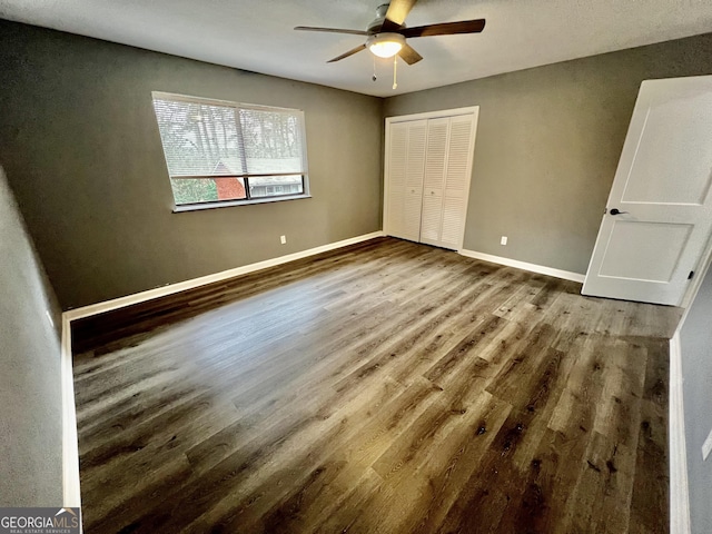 unfurnished bedroom featuring ceiling fan, a closet, and hardwood / wood-style flooring