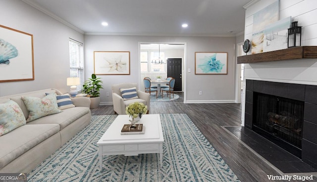 living room featuring a tiled fireplace, crown molding, and dark hardwood / wood-style flooring