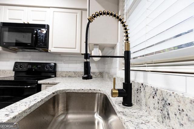 details with white cabinetry, light stone countertops, tasteful backsplash, and black appliances