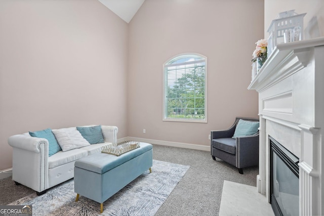 sitting room with lofted ceiling, carpet floors, a fireplace with flush hearth, and baseboards