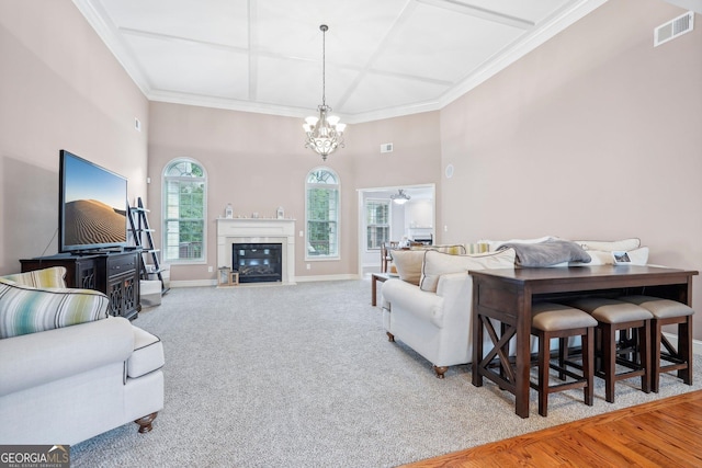 living area with visible vents, baseboards, a fireplace with flush hearth, ornamental molding, and carpet floors