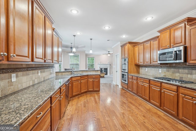 kitchen with stainless steel appliances, brown cabinetry, a sink, and crown molding